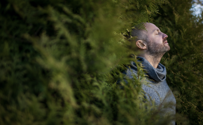 man breathing in whilst in the middle of nature