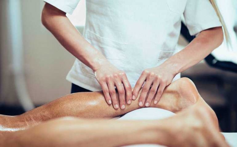 Sports Massage - Massage therapist working with patient, massaging his calves. Toned image.