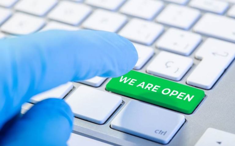 We are open concept. Hand with protective glove typing a keyboard with green key